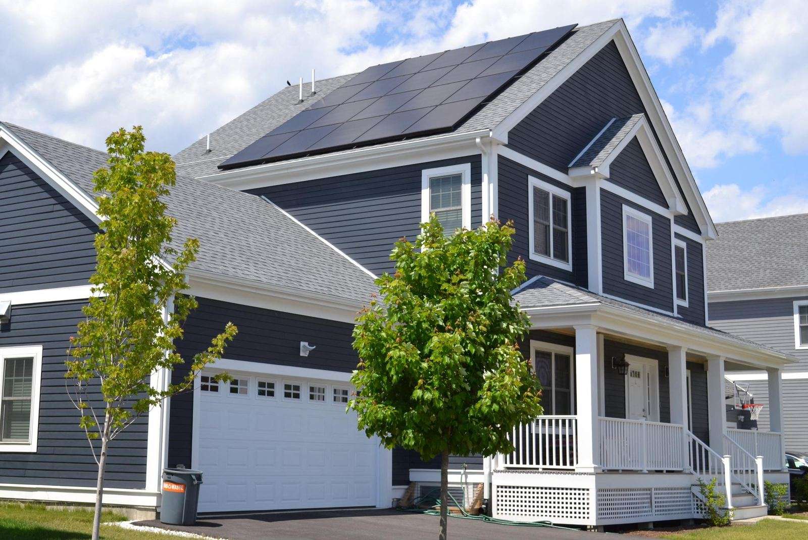 Gray two-story colonial home with an all-black solar array