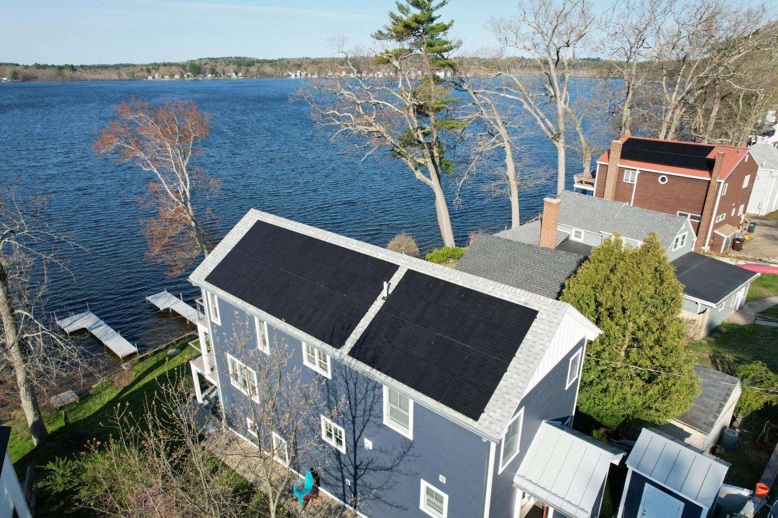 Aerial view of a lakefront home with all-black solar panels