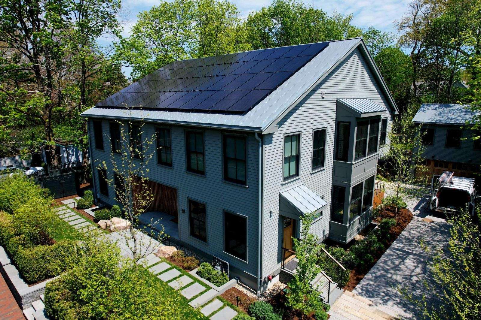 Blue-gray modern home with all-black solar panels on the roof