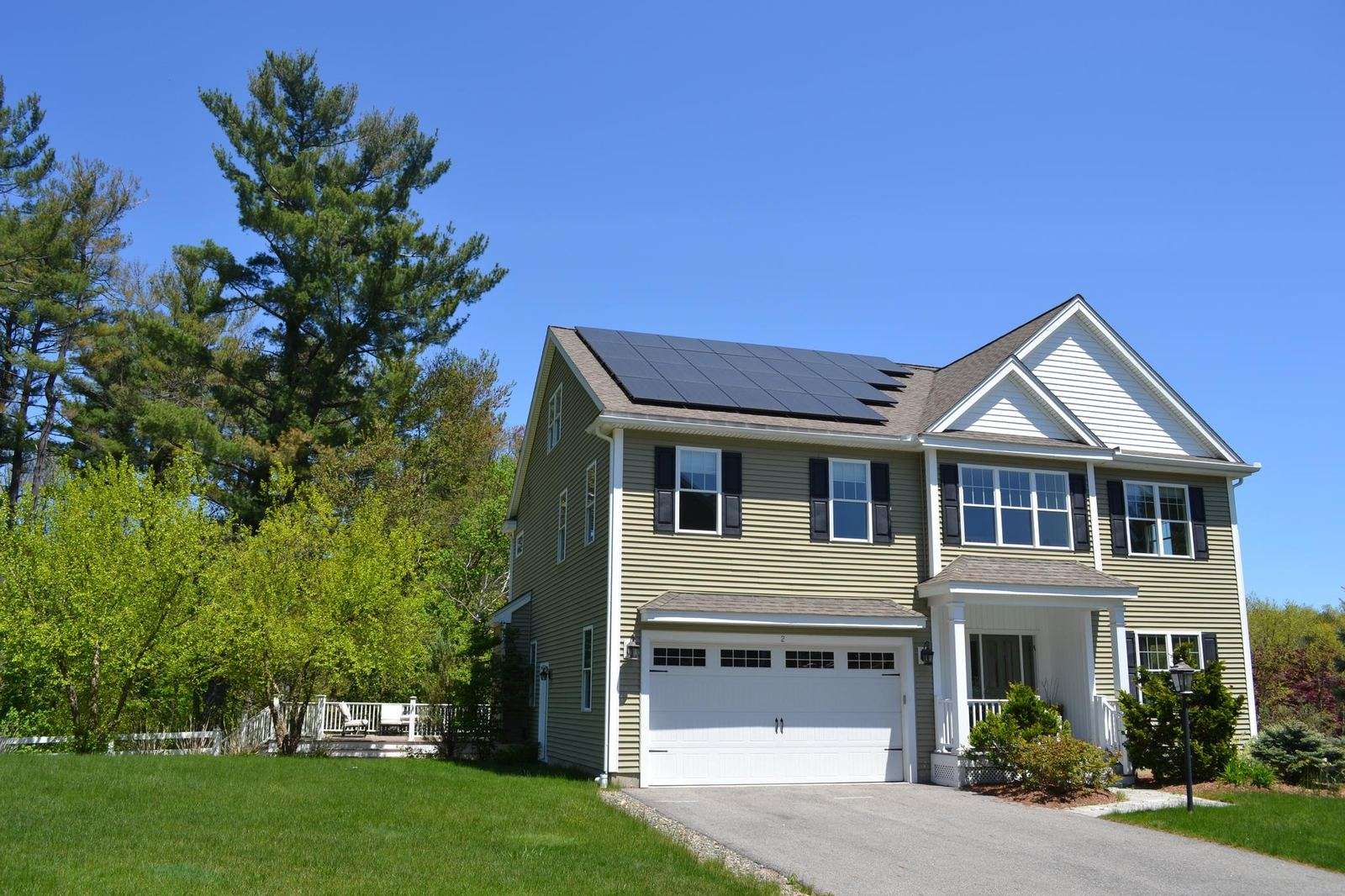 Two-story home with all-black solar panels above the garage