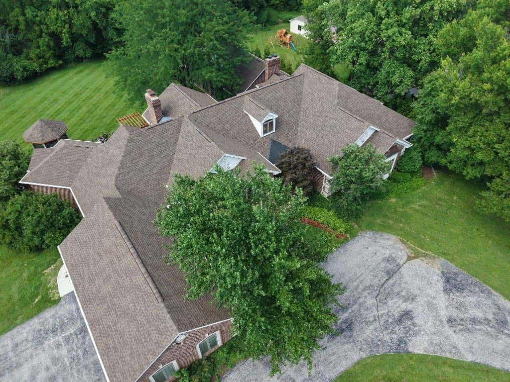 Drone view of a large shingle roof surrounded by trees