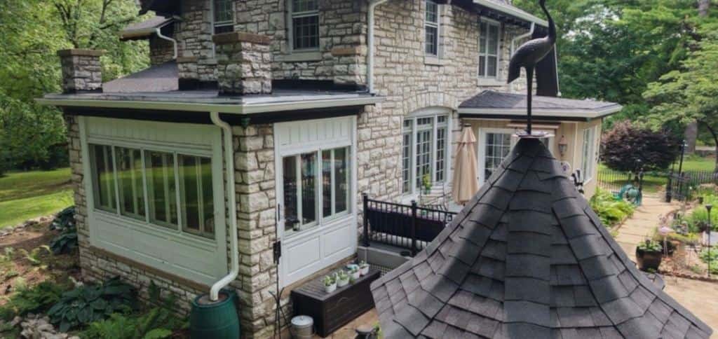 New roof on a stone home with a turret and sunroom