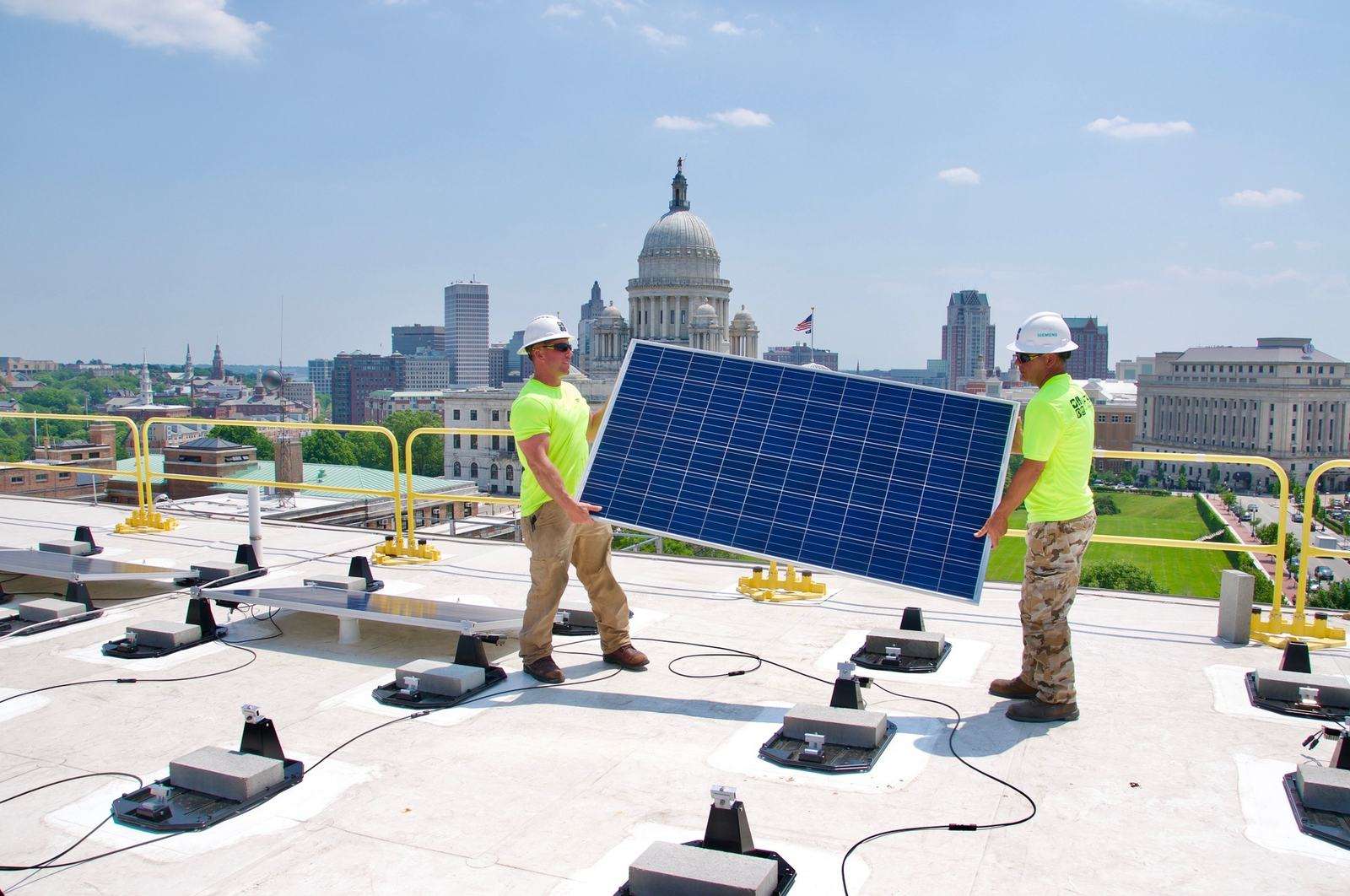 Installers carrying a solar panel across a commercial flat roof
