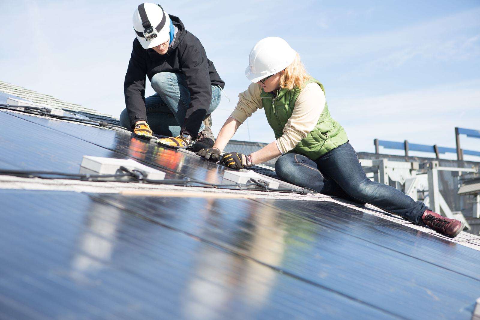 Installers in hard hats wiring solar panels