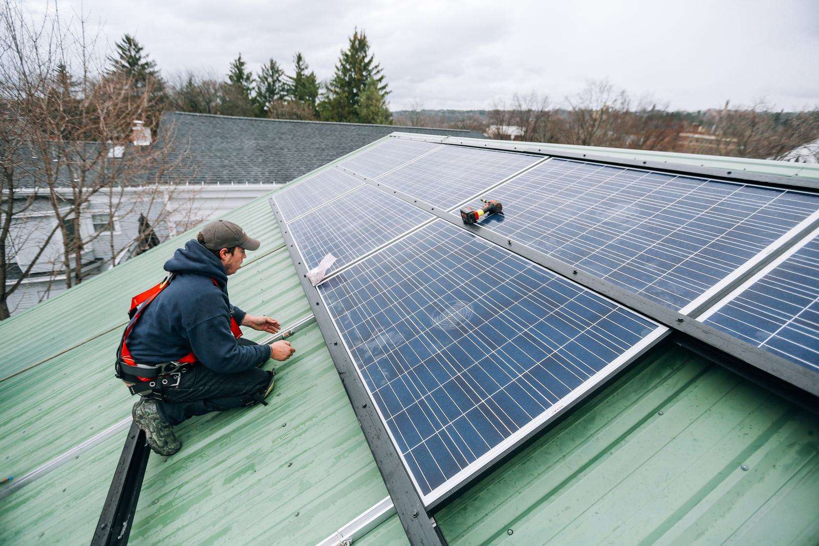 Technicians servicing solar panels on a metal roof